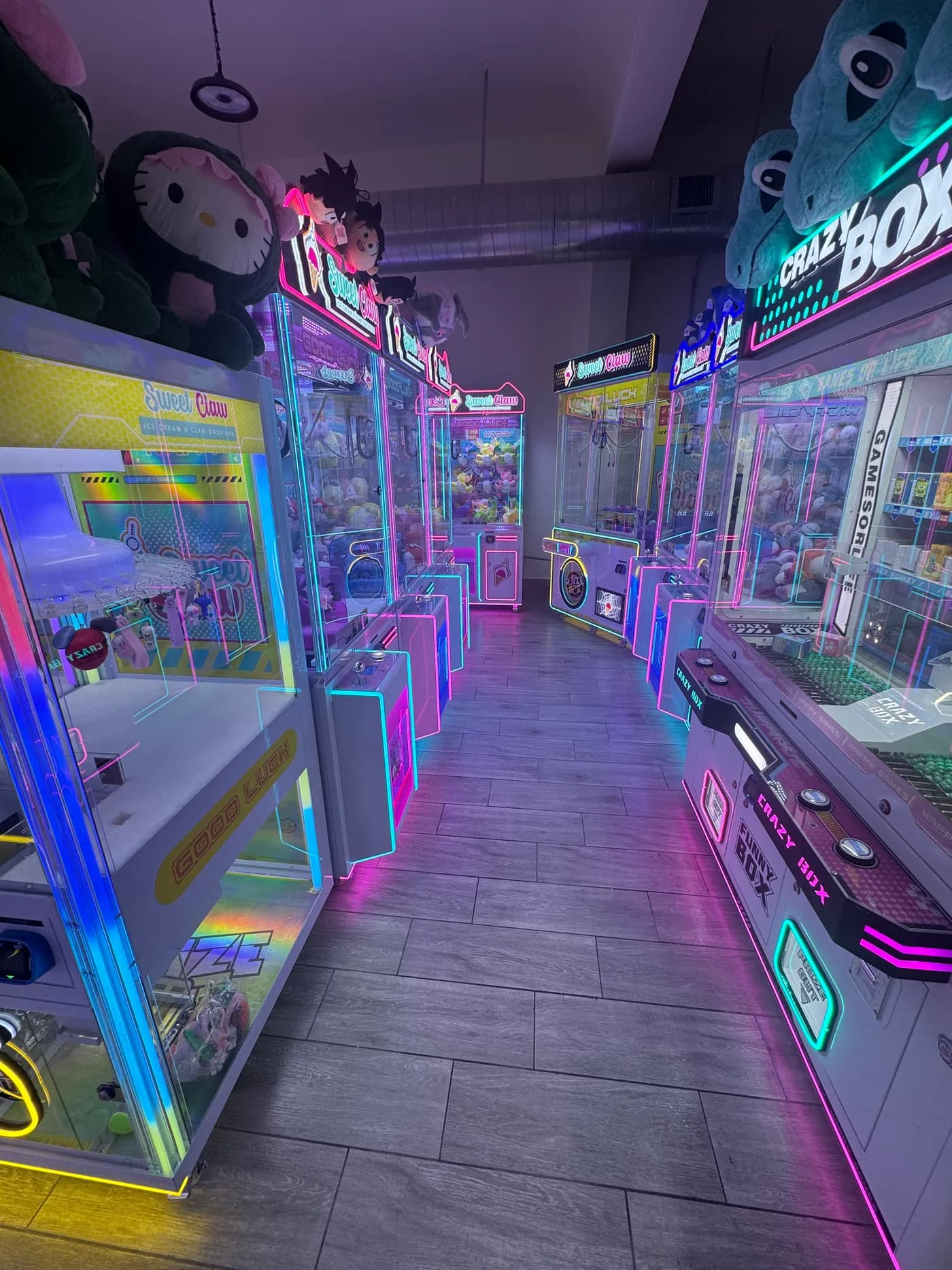 Looking down an aisle between two banks of claw machines