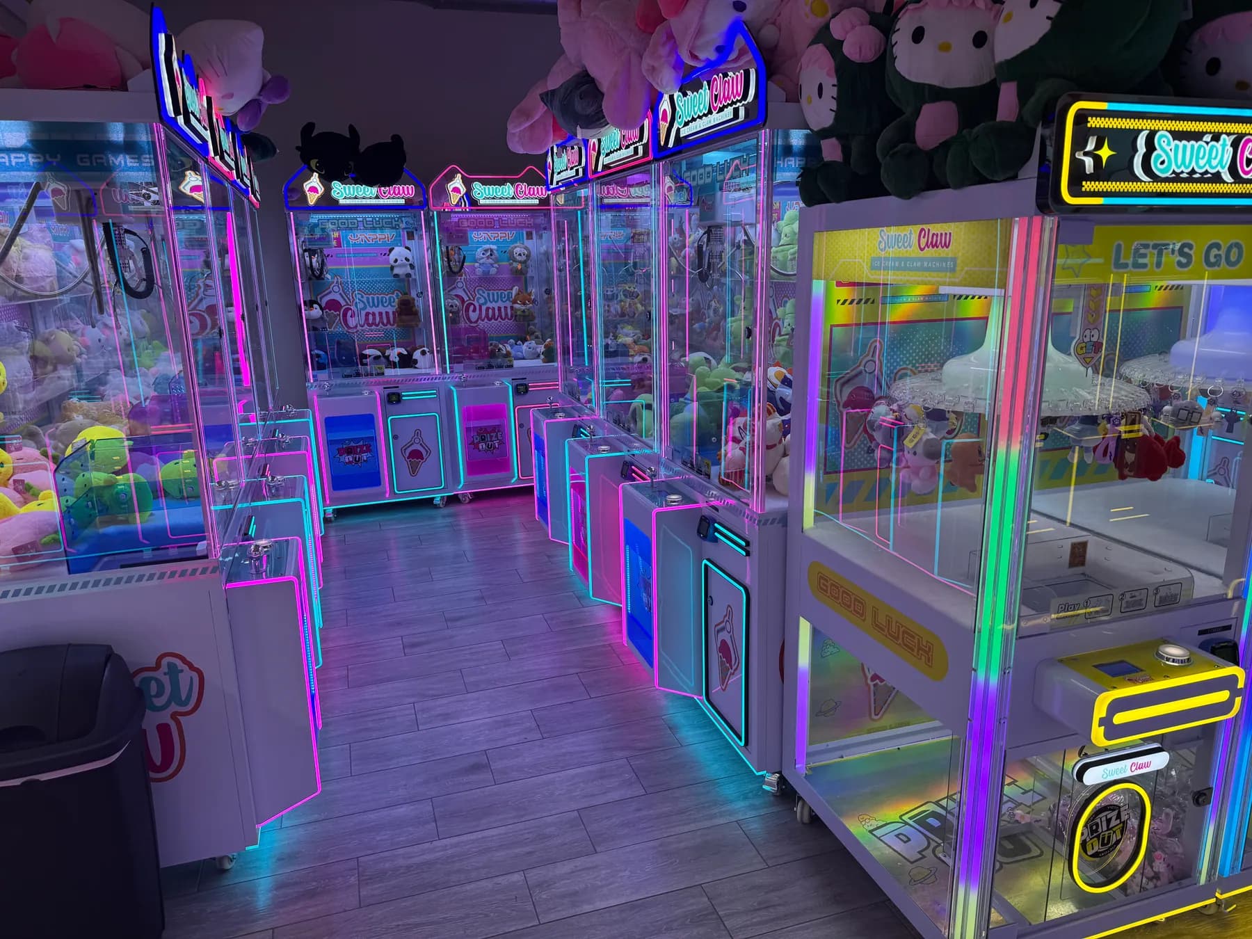 An aisle of claw machines lit in pink and cyan