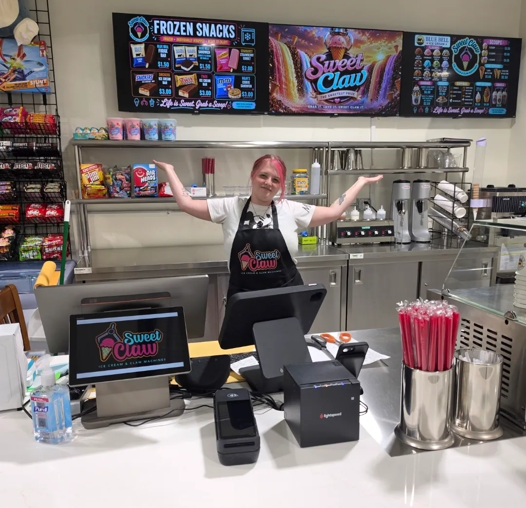 A member of staff behind the Sweet Claw counter, arms open