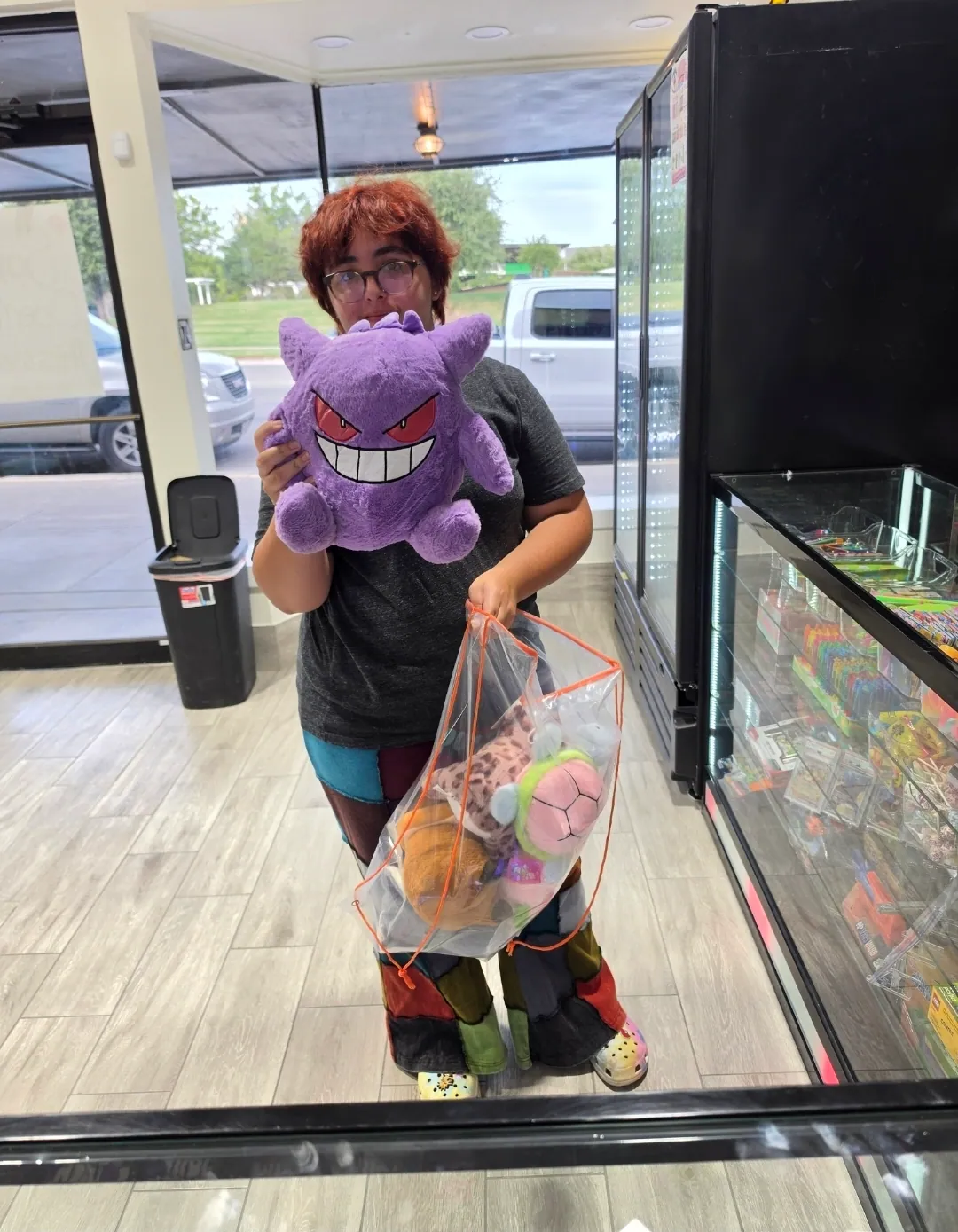 A member of staff holding a large plush toy and a full bag of won prizes