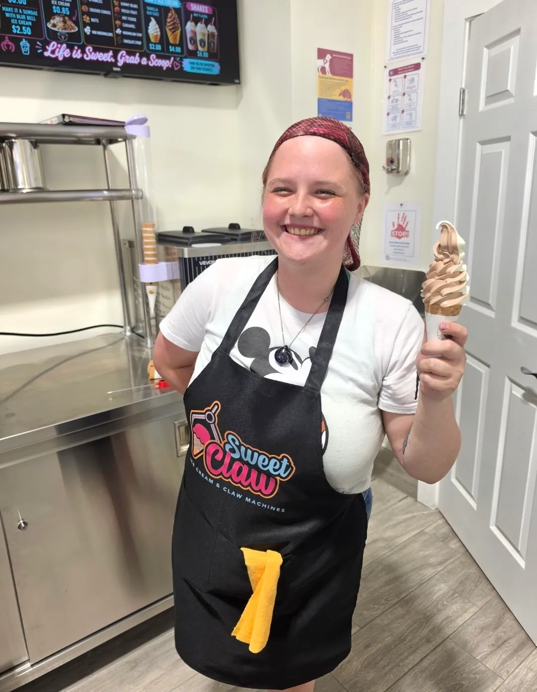 A member of staff holding up a soft serve cone behind the counter